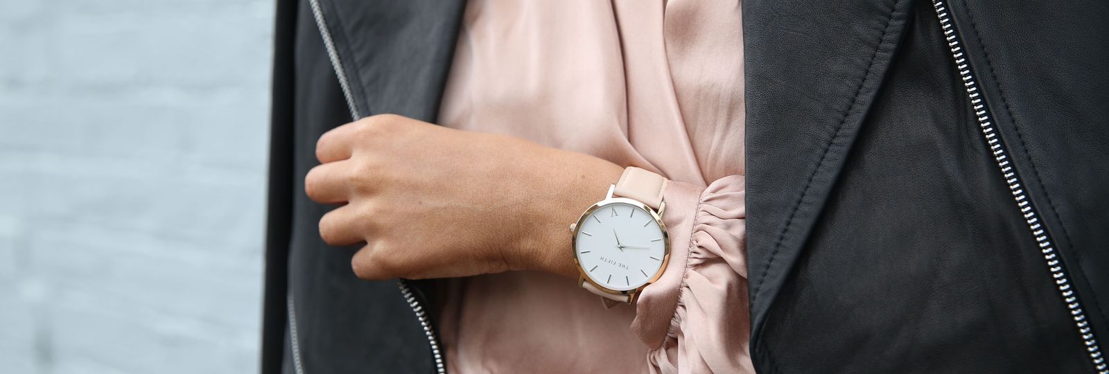 Comment choisir sa montre — montre élégante au poignet d'une femme, veste en cuir