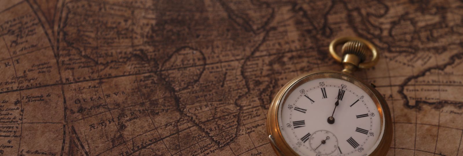 Montre de gousset ancienne posée sur une carte du monde en papier vieilli